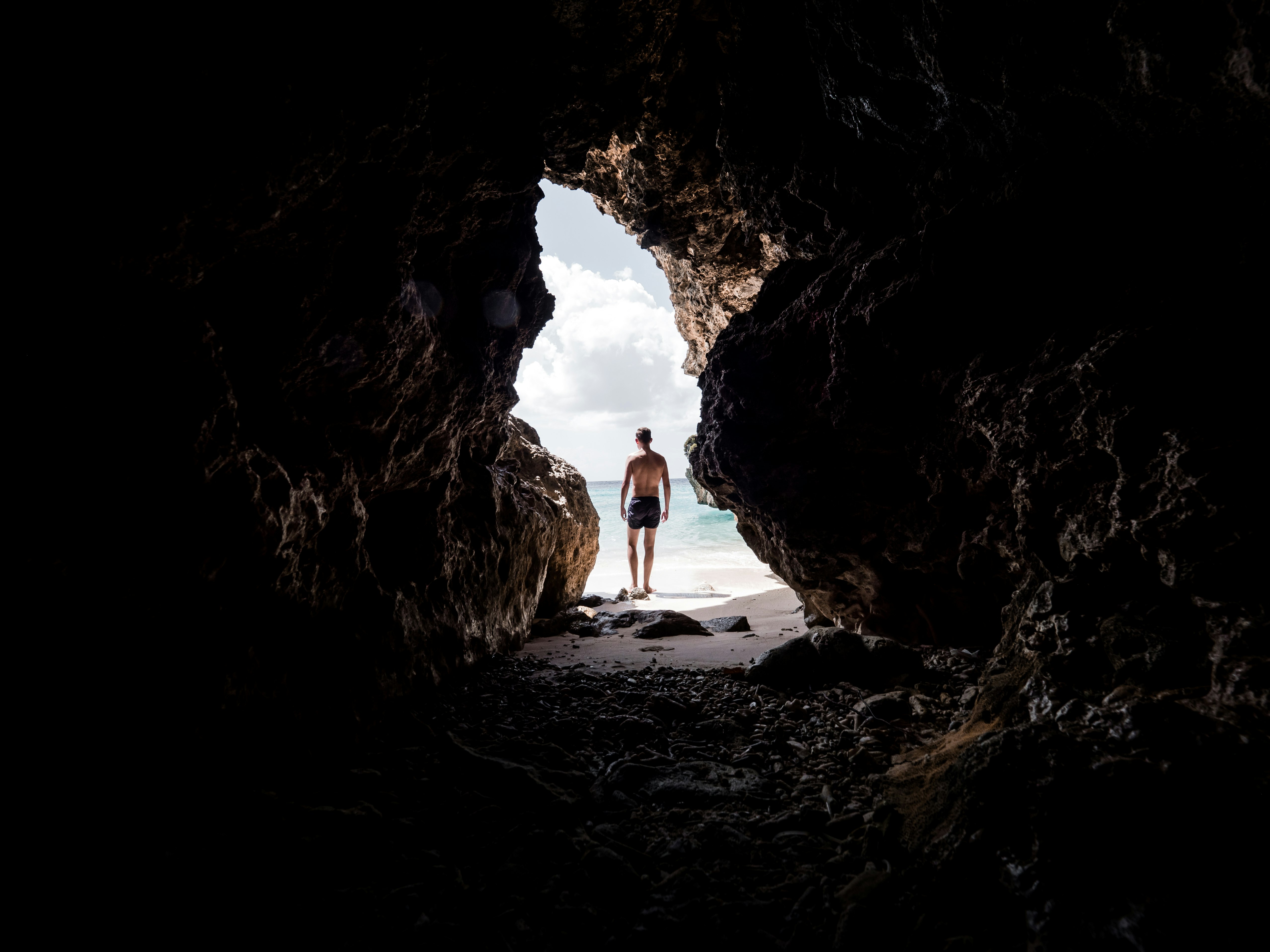 man standing in front of cave